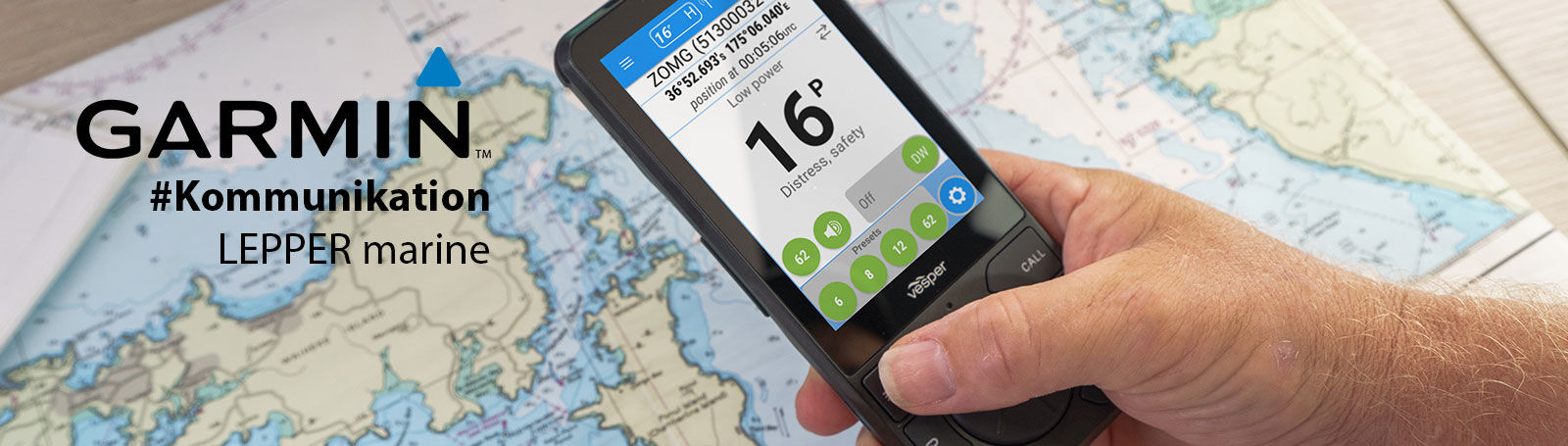 Eine Hand bedient ein Garmin VHF-Funkgerät vor einer ausgebreiteten Seekarte.