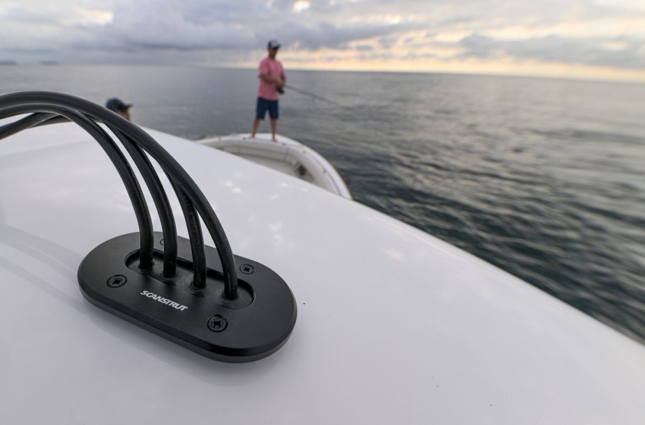 Schwarze Scanstrut Kabeldurchführung montiert auf einer weißen Bootskonsole mit vier geführten Kabeln.
