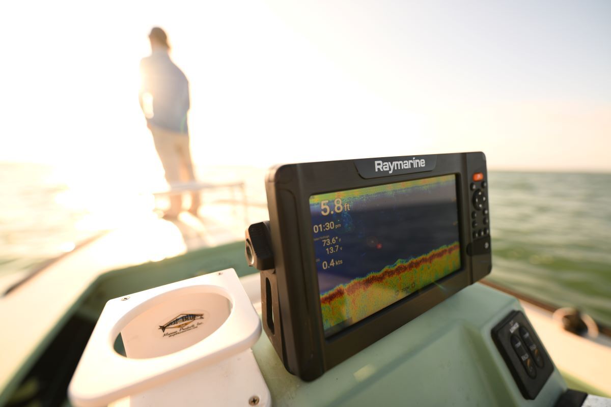 Ein Raymarine Fischfinder auf dem Armaturenbrett eines Bootes während einer Fahrt im Sonnenlicht.