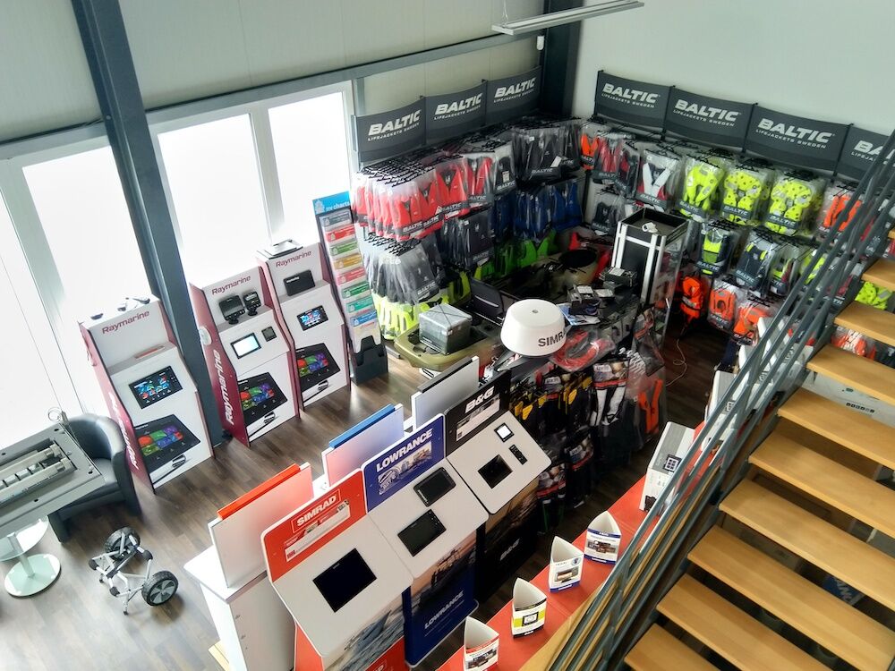 Blick von oben in ein Fachgeschäft für Wassersport mit Displays für Marineelektronik und Regalen voller Rettungswesten.