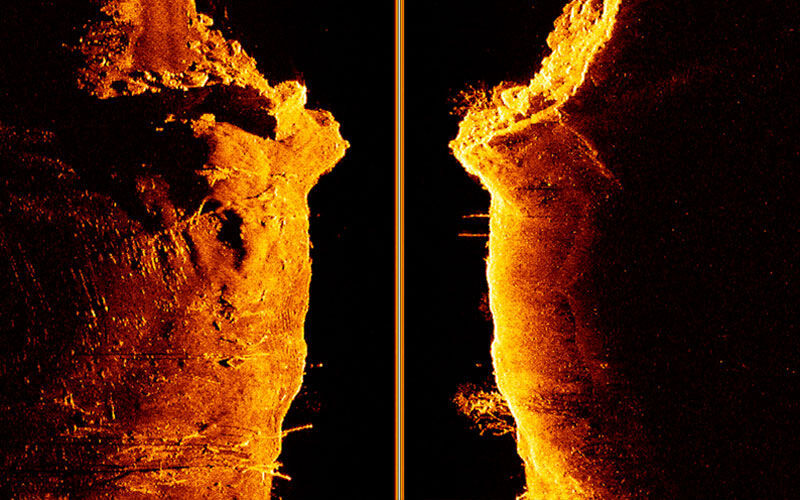 Echolot Scan einer Unterwasserstruktur in orangen Farbtönen auf schwarzem Grund mit vertikaler Trennlinie