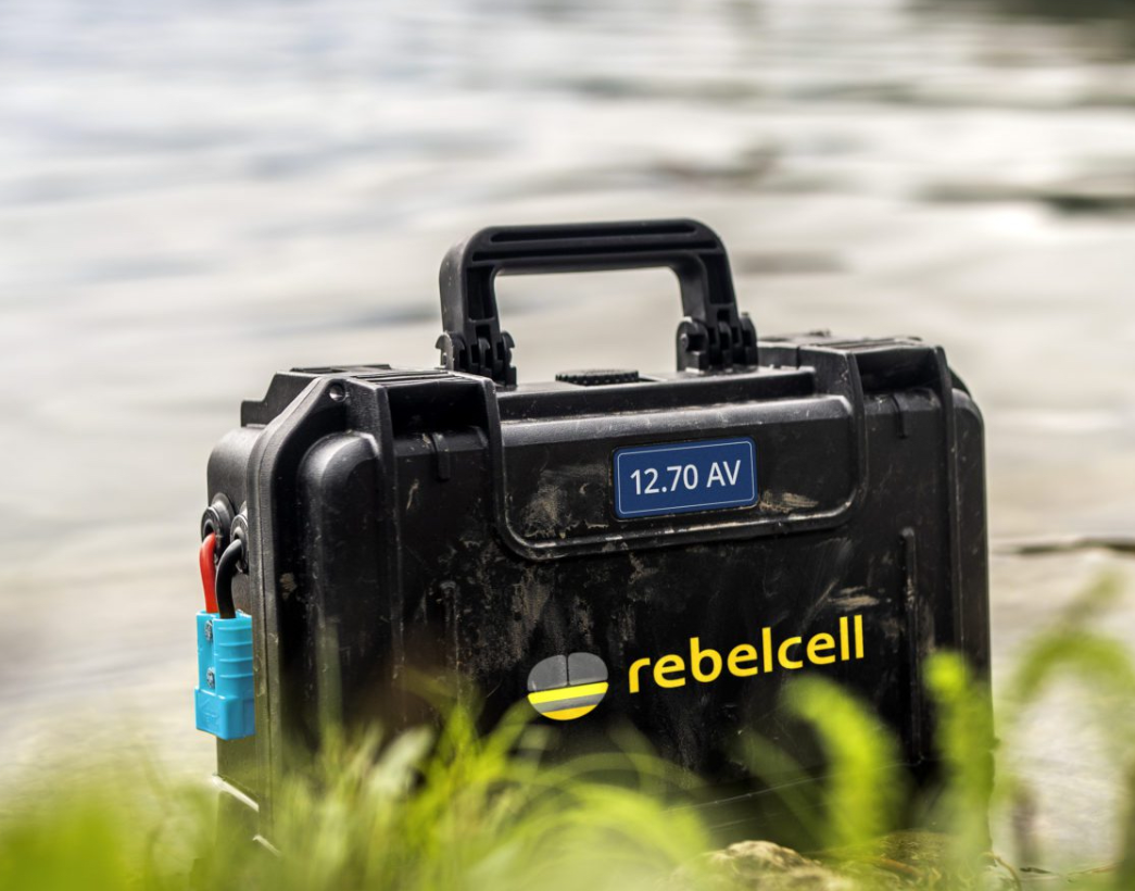 Rebelcell 12.70 AV Akku in einem schwarzen Transportkoffer am Ufer neben Wasser stehend