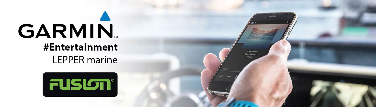 Hand hält ein Smartphone mit Musik-App im Boot, links Garmin und Fusion Logos.
